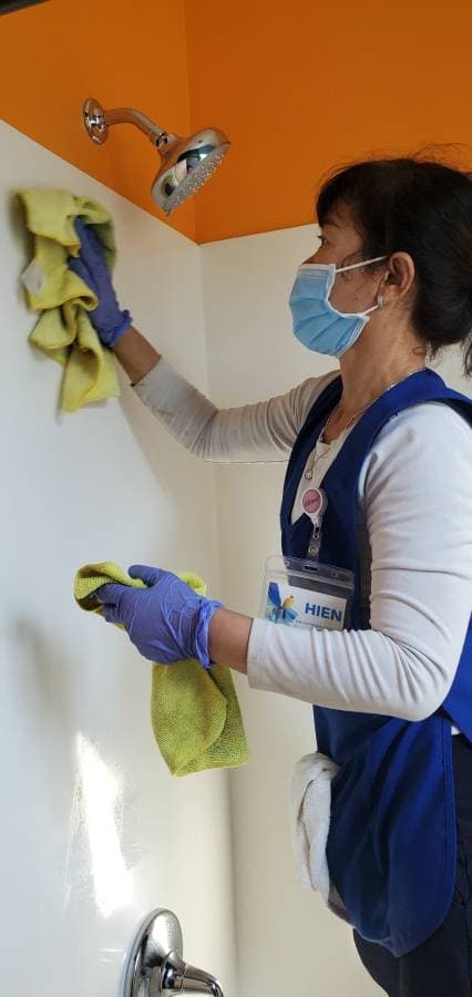 House cleaner wiping kitchen surfaces with eco-friendly cleaning products